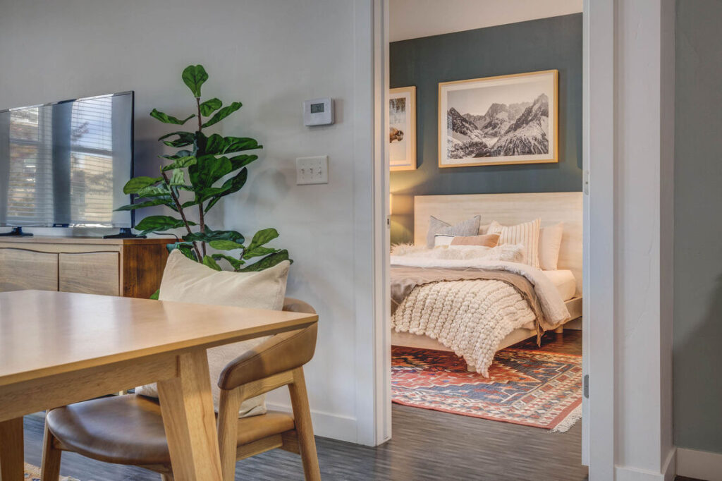 View of the bedroom and living room at Novi at Jordan Valley Station apartments in West Jordan