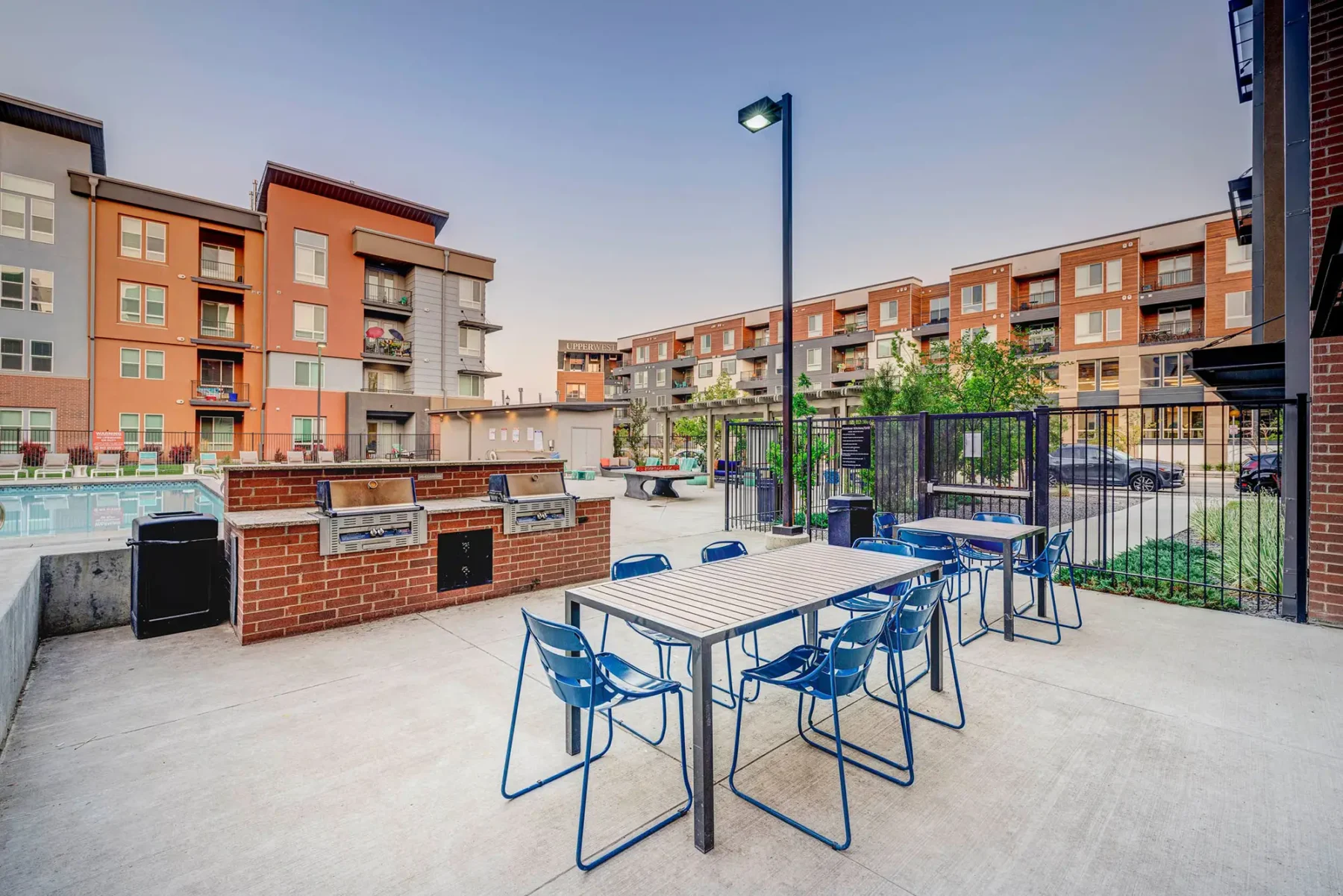 Novi at Jordan Vallery Station courtyard with two grilling stations, patio dinning tables and chairs, a swimming pool, and security fence surround