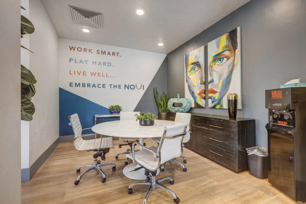 "work smart, play hard, live well, embrace the Novi" sign on back wall of clubhouse area