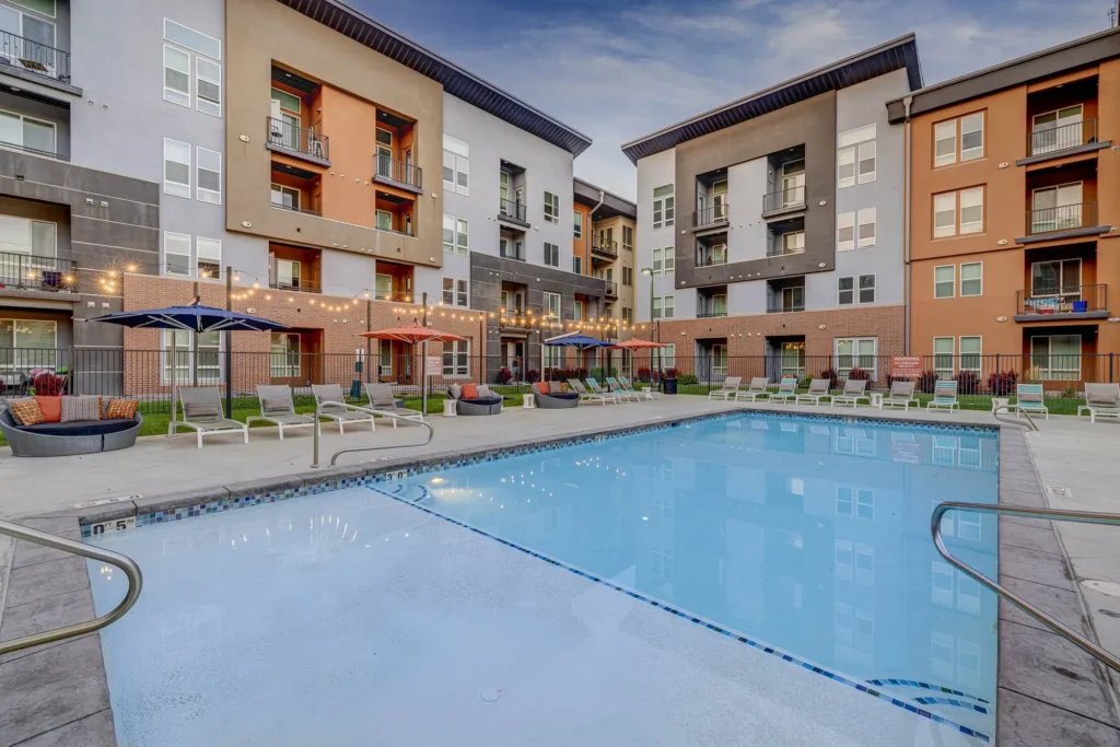pool view with lounge chairs, umbrellas, and building in the background