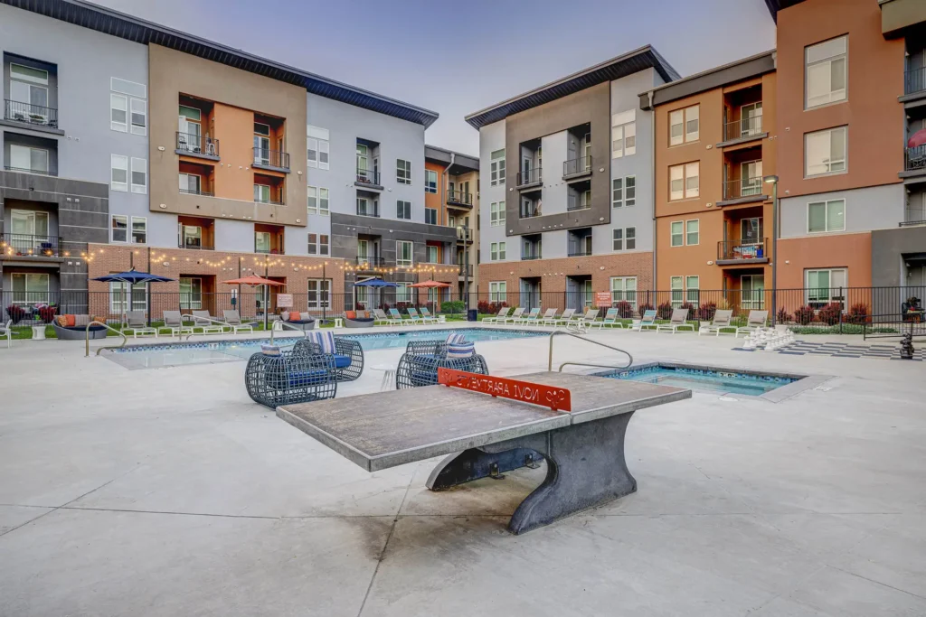 Pool courtyard with ping pong table, hot tub, and building in the background